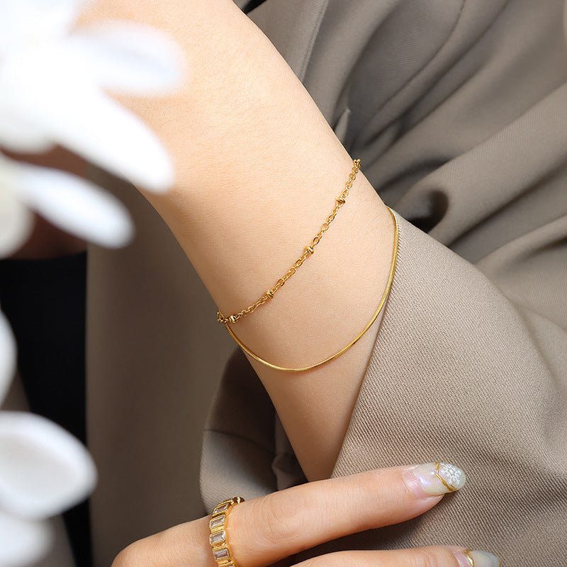 Elegant gold double layer bracelet styled on the wrist with a soft neutral outfit