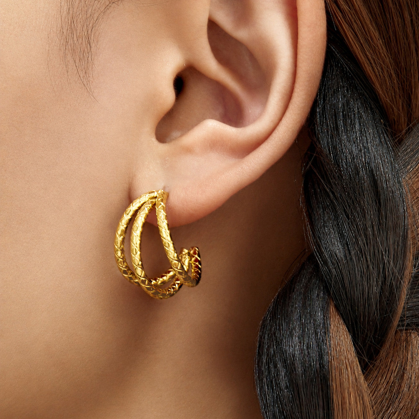 Side view of a model wearing gold double layer hoop earrings with a rounded C-shaped profile