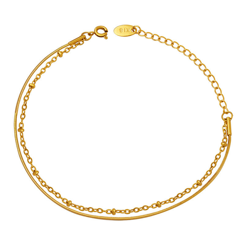 Gold double layer bracelet with a snake chain and bead chain shown in a clean flat lay product photo