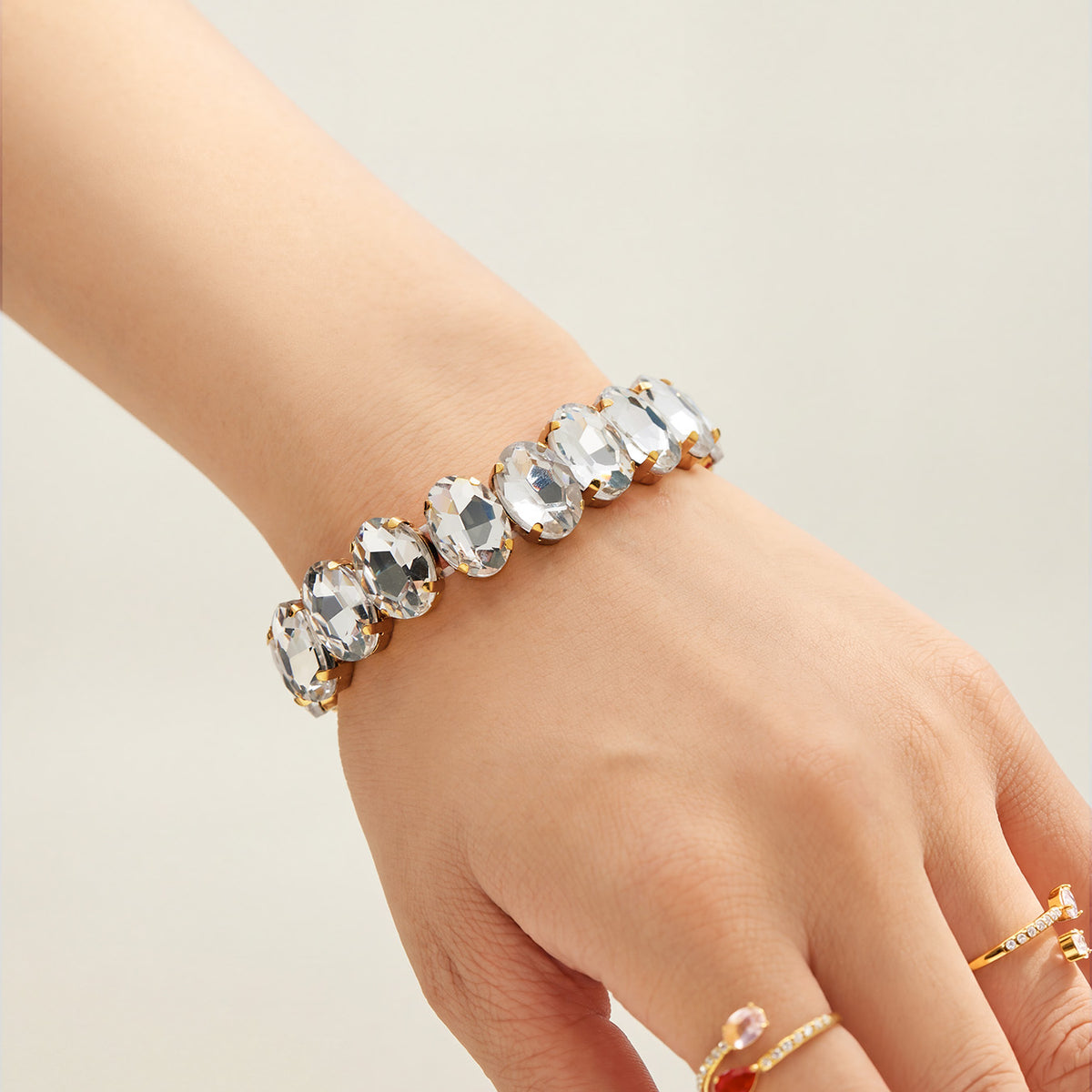 Gold-tone stretch bracelet with clear faceted glass rhinestones styled on hand