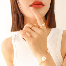 Model wearing a gold-tone faux pearl open ring in a close-up hand styling shot