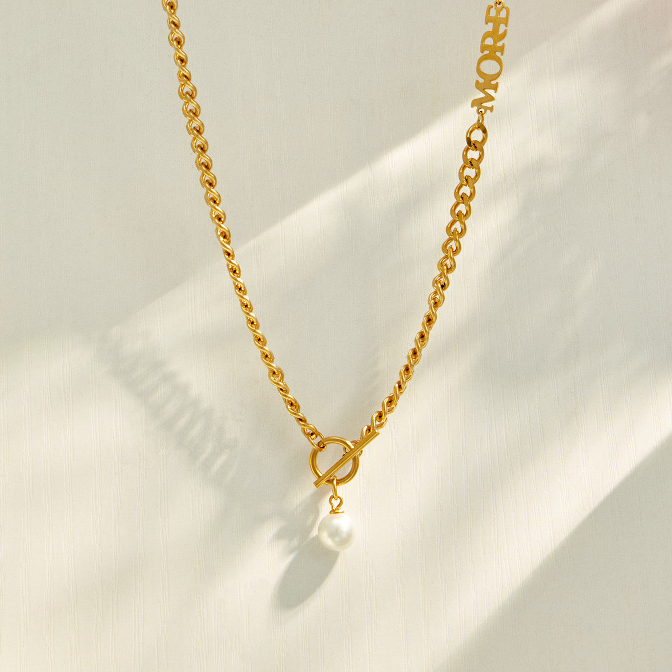 Gold faux pearl Y necklace with a delicate vertical drop displayed on neutral fabric