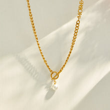 Gold faux pearl Y necklace with a delicate vertical drop displayed on neutral fabric