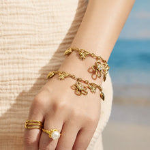 Gold floral butterfly charm bracelets layered together on a model wrist