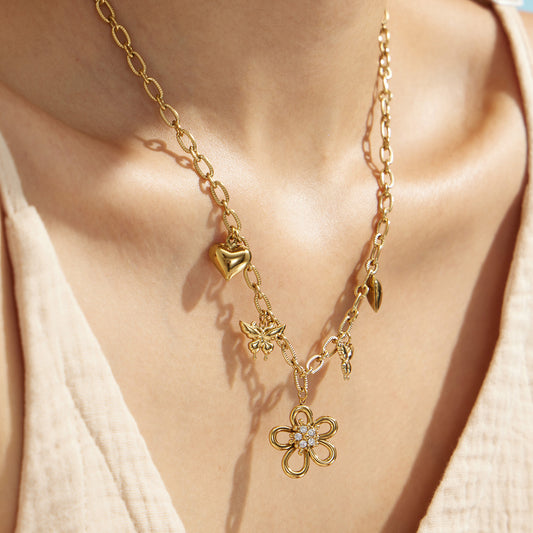 Gold floral butterfly charm necklace with zircon flower details worn at the neckline