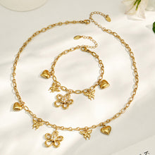Gold floral charm necklace and matching butterfly bracelet displayed together on a light background