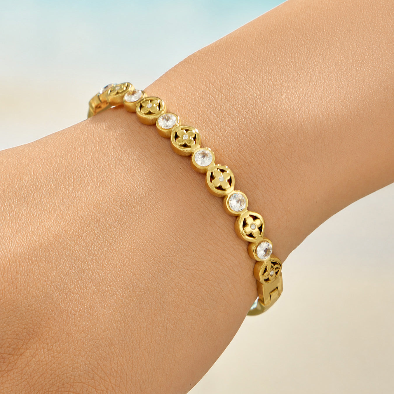 Close-up of a model wearing a gold floral cubic zirconia bangle