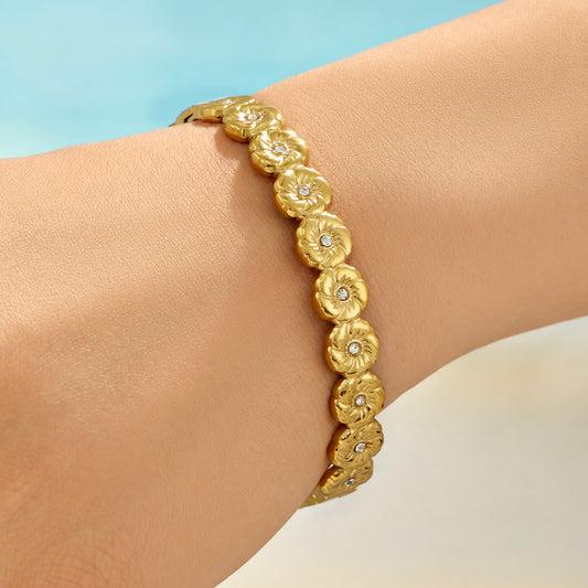 Model wearing a gold floral hinged bangle with clear cubic zirconia accents