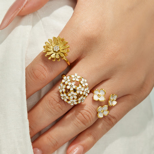 Model wearing multiple 18K PVD gold floral rings with cubic zirconia and flower details