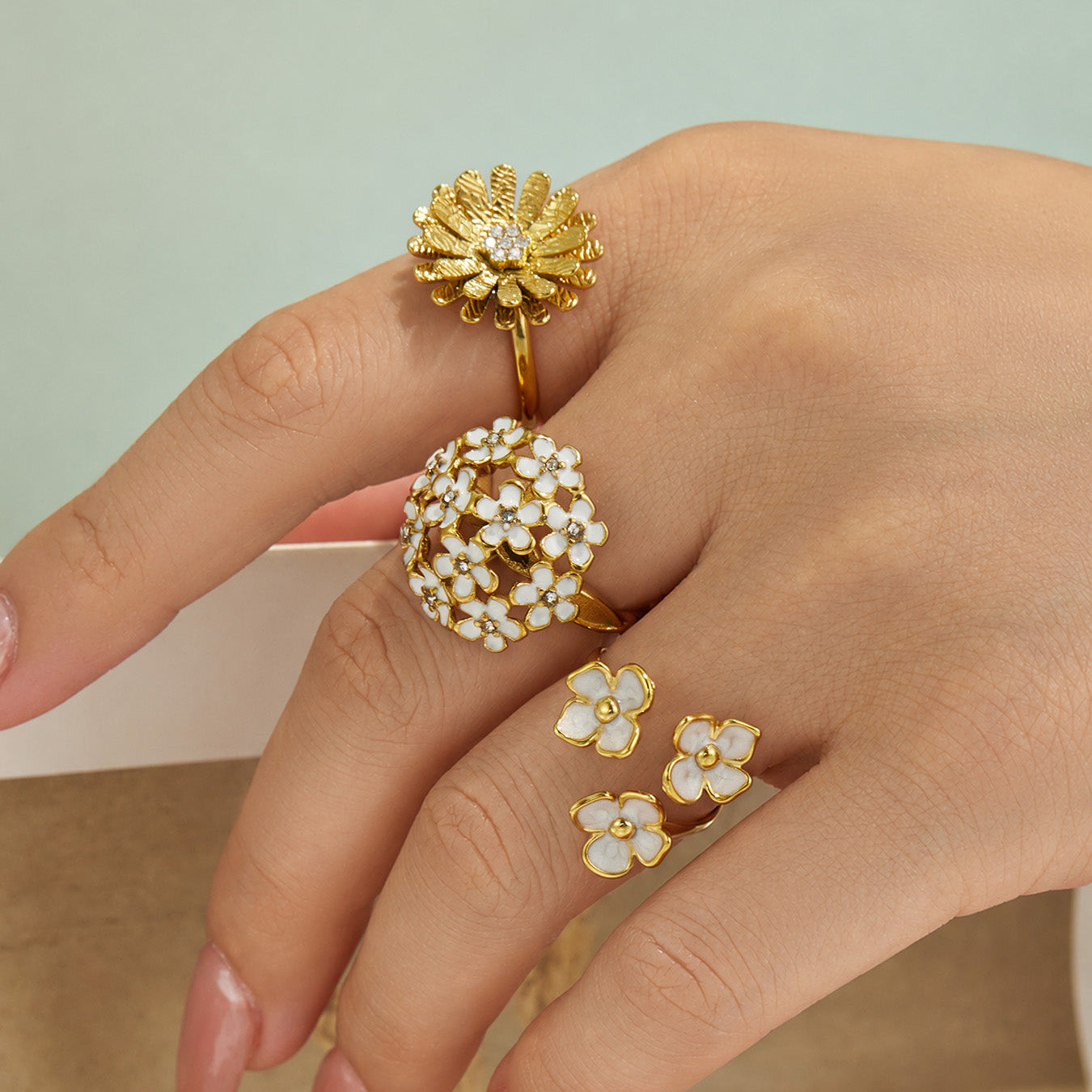 Model wearing gold floral cubic zirconia rings in a coordinated botanical jewelry look
