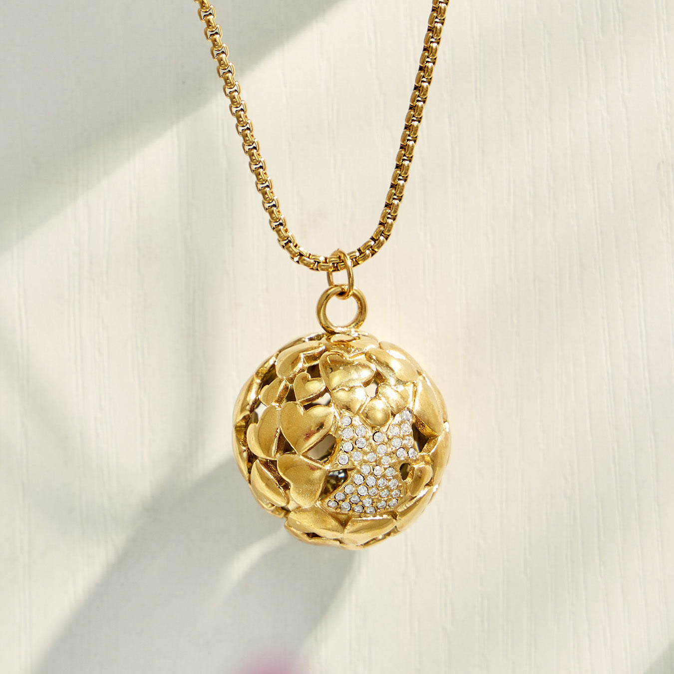 Gold floral medallion pendant necklace displayed on a soft neutral background