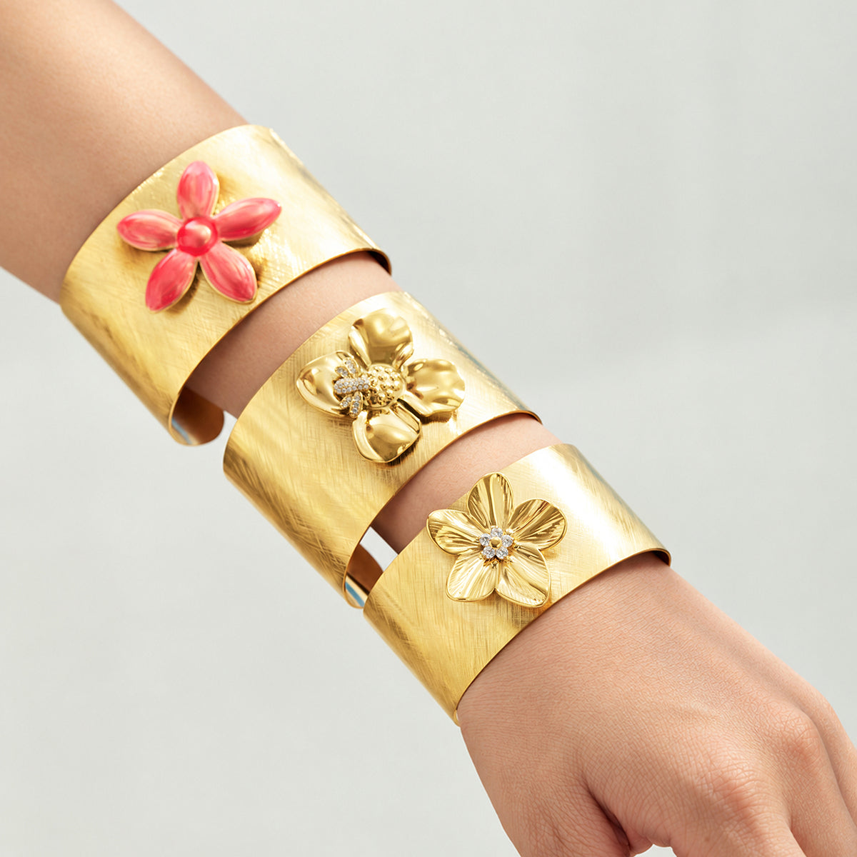 Gold-tone stainless steel floral open cuff bangles styled together on arm