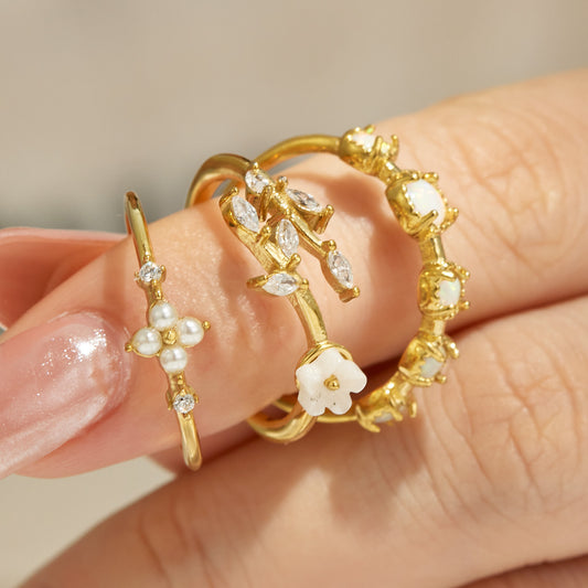 Hand model wearing a 316L stainless steel floral ring collection in 18K PVD gold with elegant feminine styling