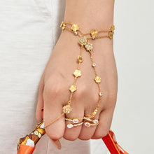 Gold-tone floral hand chain bracelet with connected finger rings worn on hand