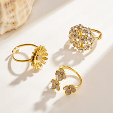 Three gold floral ring styles with daisy, enamel and cubic zirconia details displayed on a light background