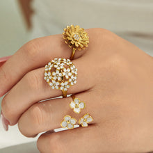 Model styling multiple gold floral rings with daisy, enamel and cubic zirconia details
