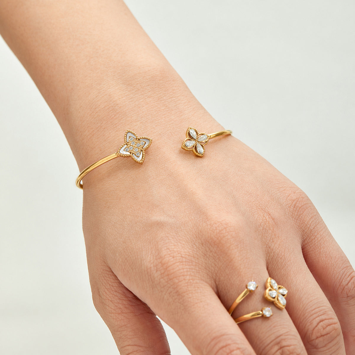 Gold-tone floral open bangle worn with matching flower open rings