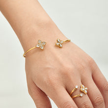 Gold-tone floral open bangle worn with matching flower open rings