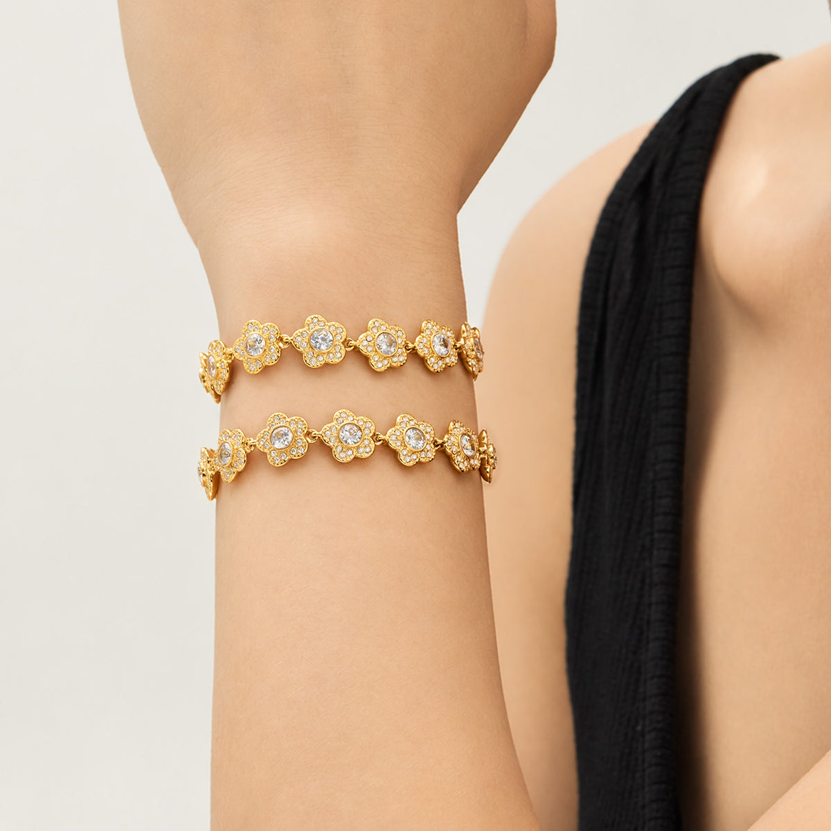 Gold flower bracelets with cubic zirconia details styled together on wrist