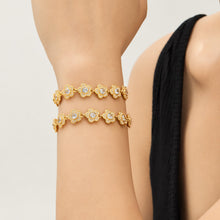 Gold flower bracelets with cubic zirconia details styled together on wrist