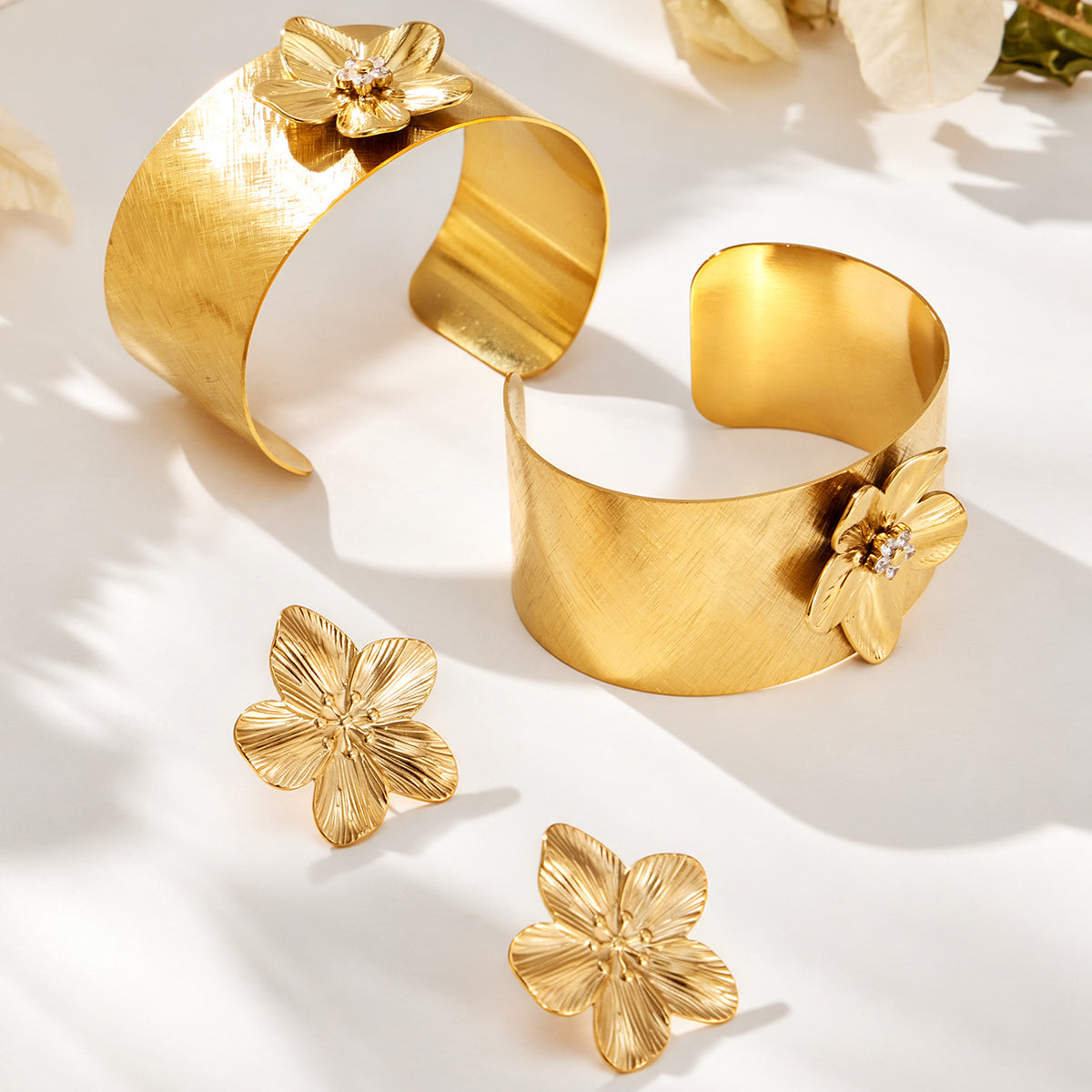 Matching gold flower cuff bangles and flower earrings displayed together