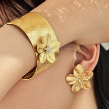 Gold-tone stainless steel flower cuff bangle worn on arm