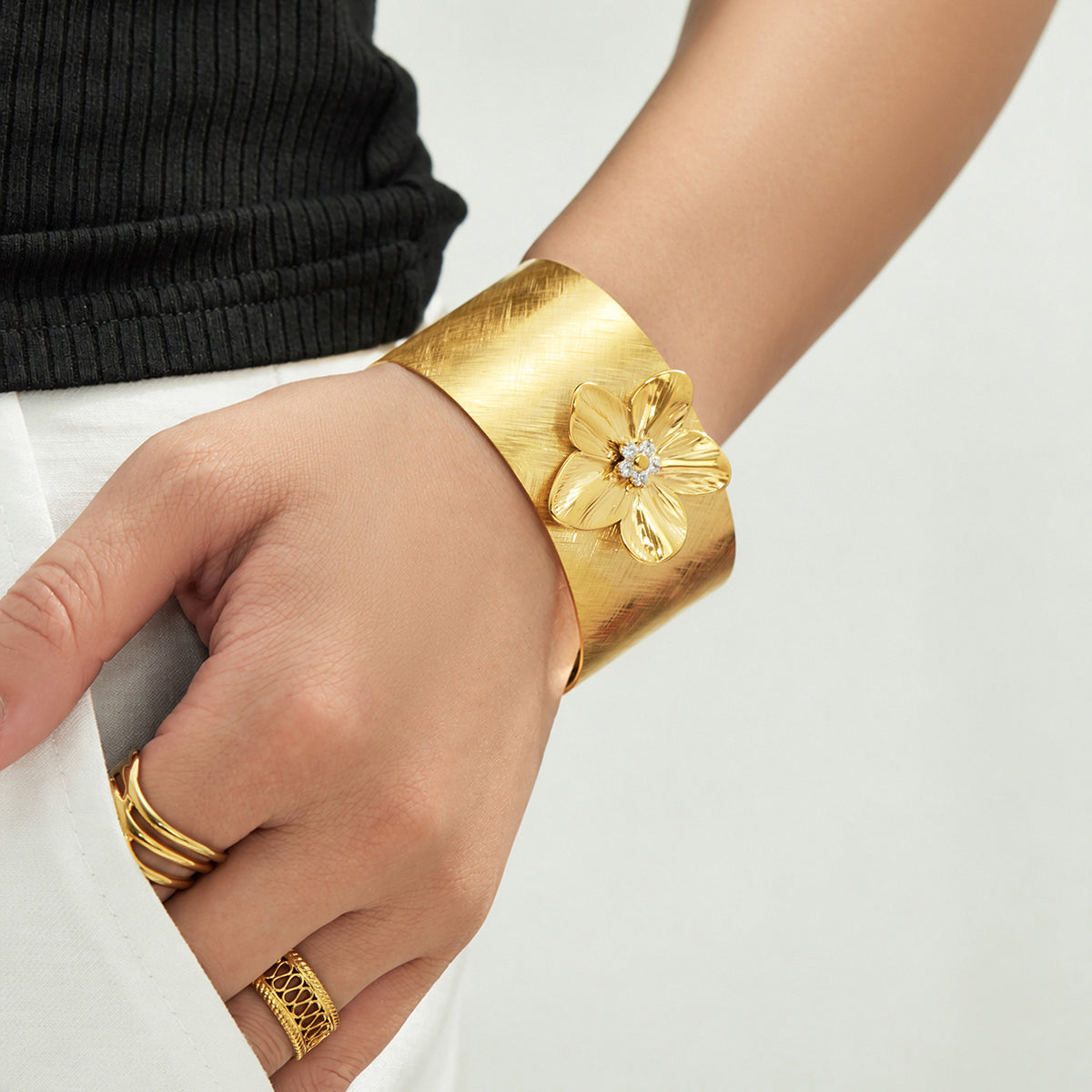 Gold-tone flower cuff bangle with sculptural floral detail worn on wrist
