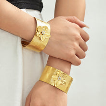 Statement gold flower cuff bangles with textured floral motifs worn on wrist