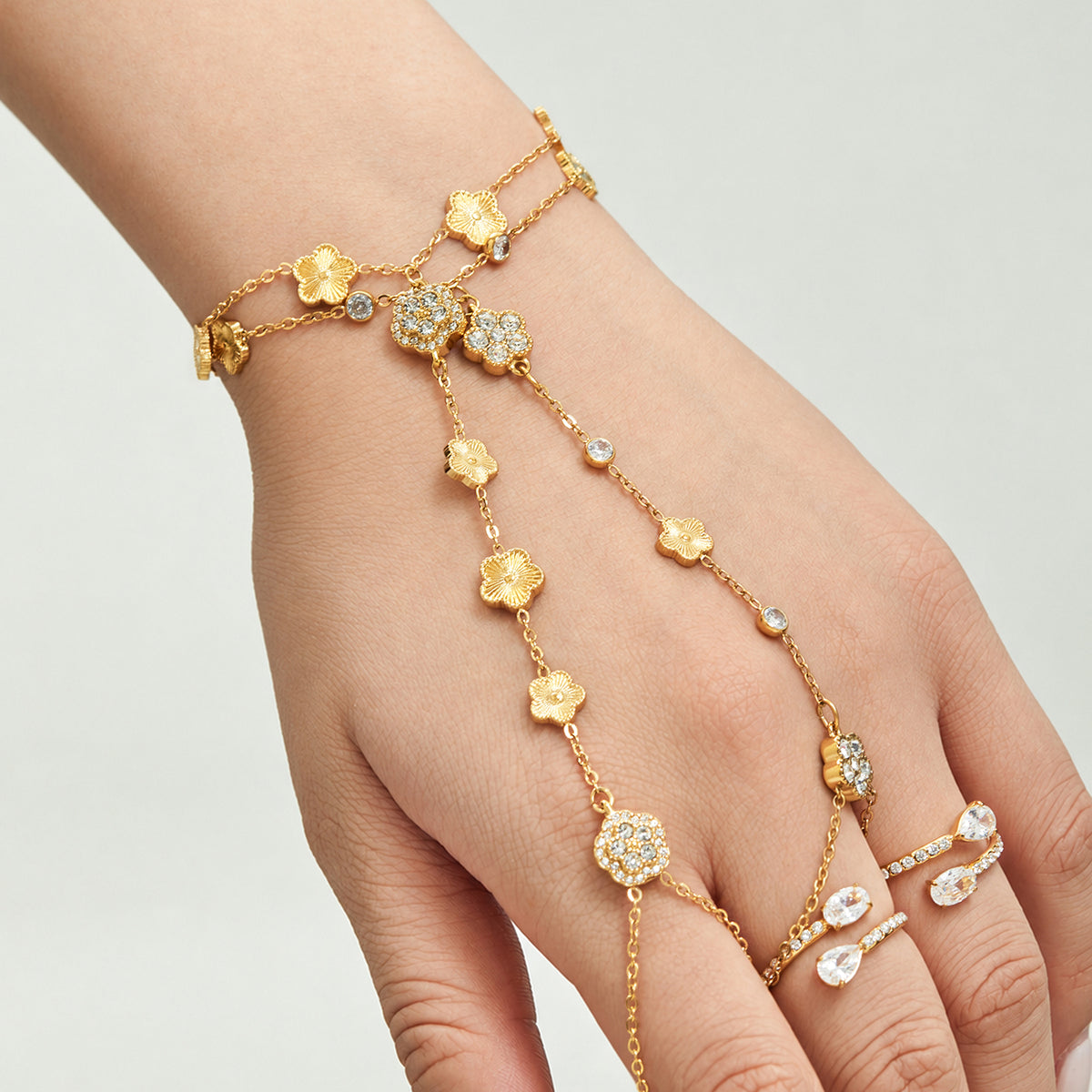 Gold-tone stainless steel flower hand chain bracelet styled across the hand