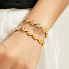 Gold flower link bracelets with cubic zirconia accents layered on the wrist