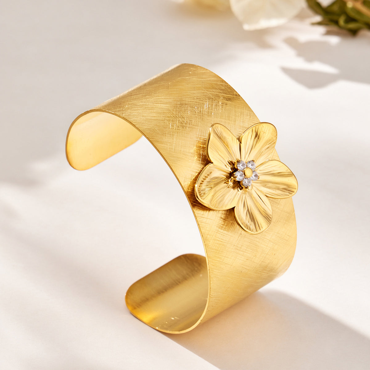 Gold-tone stainless steel open cuff bangle with raised flower detail