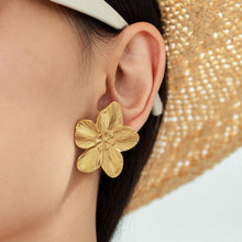 Gold flower statement earrings with textured metal petals worn by model