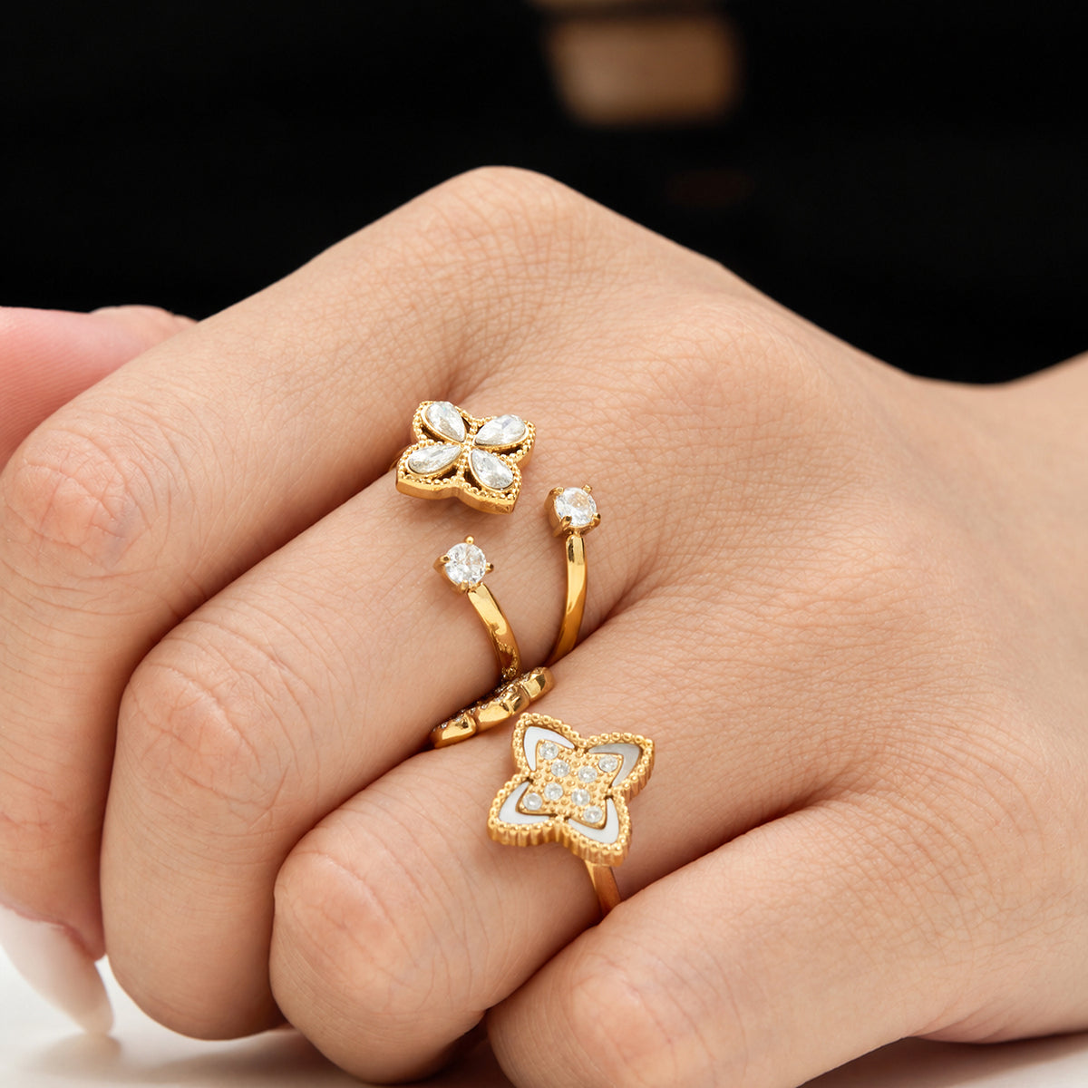 Gold-tone open rings with four-petal flower and zircon details worn together on the hand