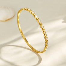 Angled product view of a gold geometric bangle with zircon accents