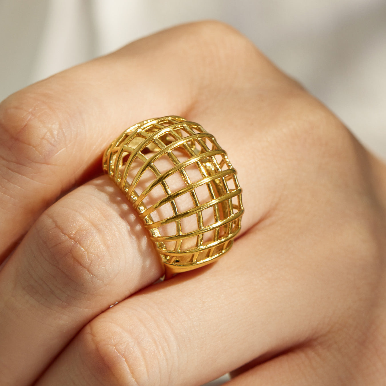 Close-up of a gold tone geometric cage 316L stainless steel statement ring
