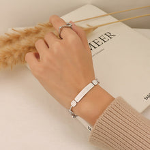 Gold geometric chain bracelet worn on the wrist with polished square accents