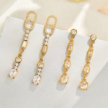 Gold geometric cubic zirconia drop earrings displayed on a neutral background