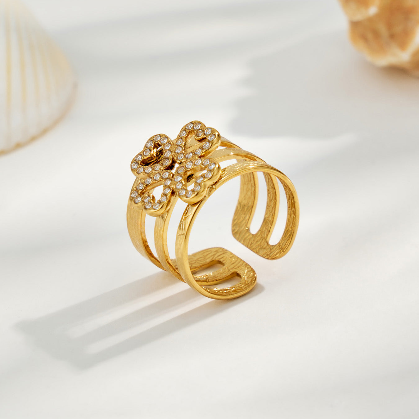 Gold 316L stainless steel geometric open ring with cubic zirconia details on a white display