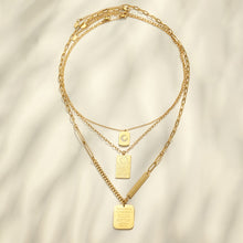 Gold square and rectangular pendant necklaces arranged in a layered flat lay