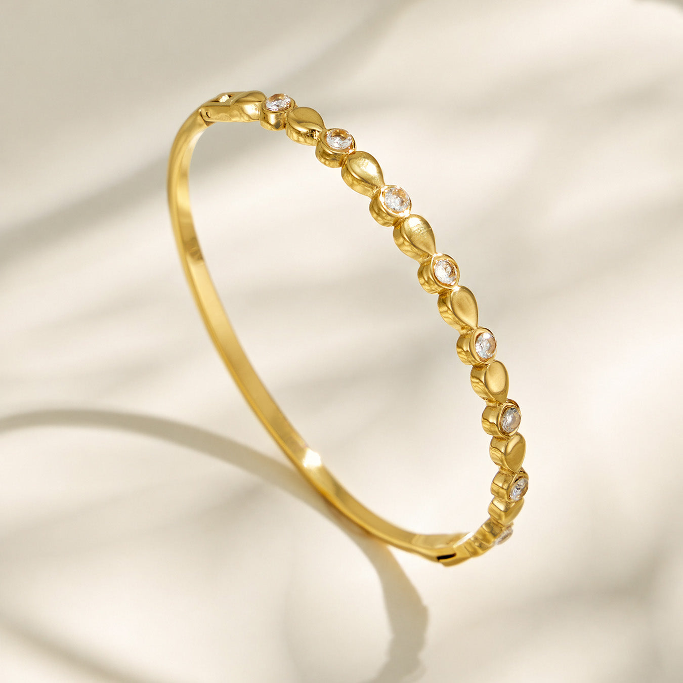 Gold geometric zircon bangle shown upright on a light neutral background