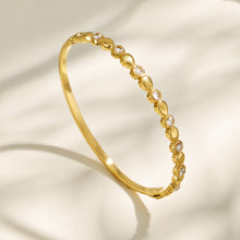 Gold geometric zircon bangle shown upright on a light neutral background