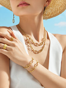Gold D-shaped zircon necklace and matching drop earrings worn on neckline for elegant resort jewelry styling