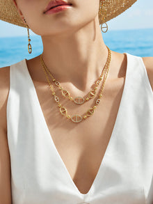 Detail view of gold geometric D-shaped zircon drop earrings worn on ear with sparkling zircon accents