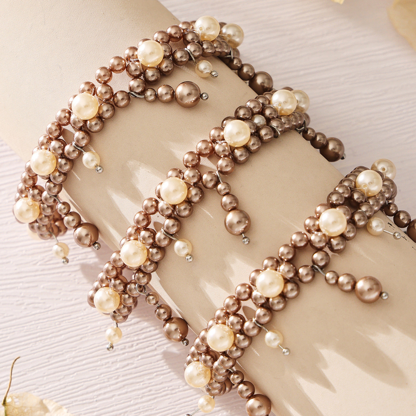 Gold and gray double-row shell pearl bracelets arranged on a neutral fabric background