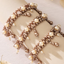 Gold and gray double-row shell pearl bracelets arranged on a neutral fabric background