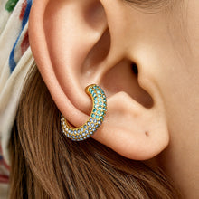 Close-up of gold C-shaped ear cuff with green cubic zirconia