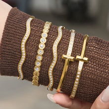 Gold zircon cuff bangle bracelet stack worn on wrist with H buckle bracelet and wavy zircon bracelet for boutique jewelry display