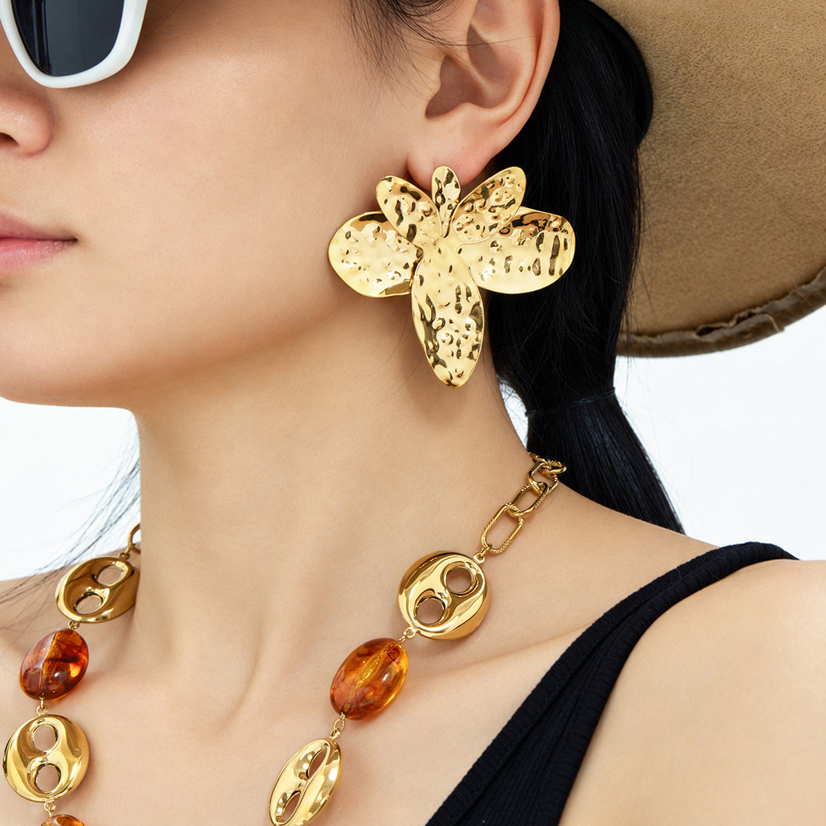 Gold hammered flower earrings with oversized floral silhouette worn on ear