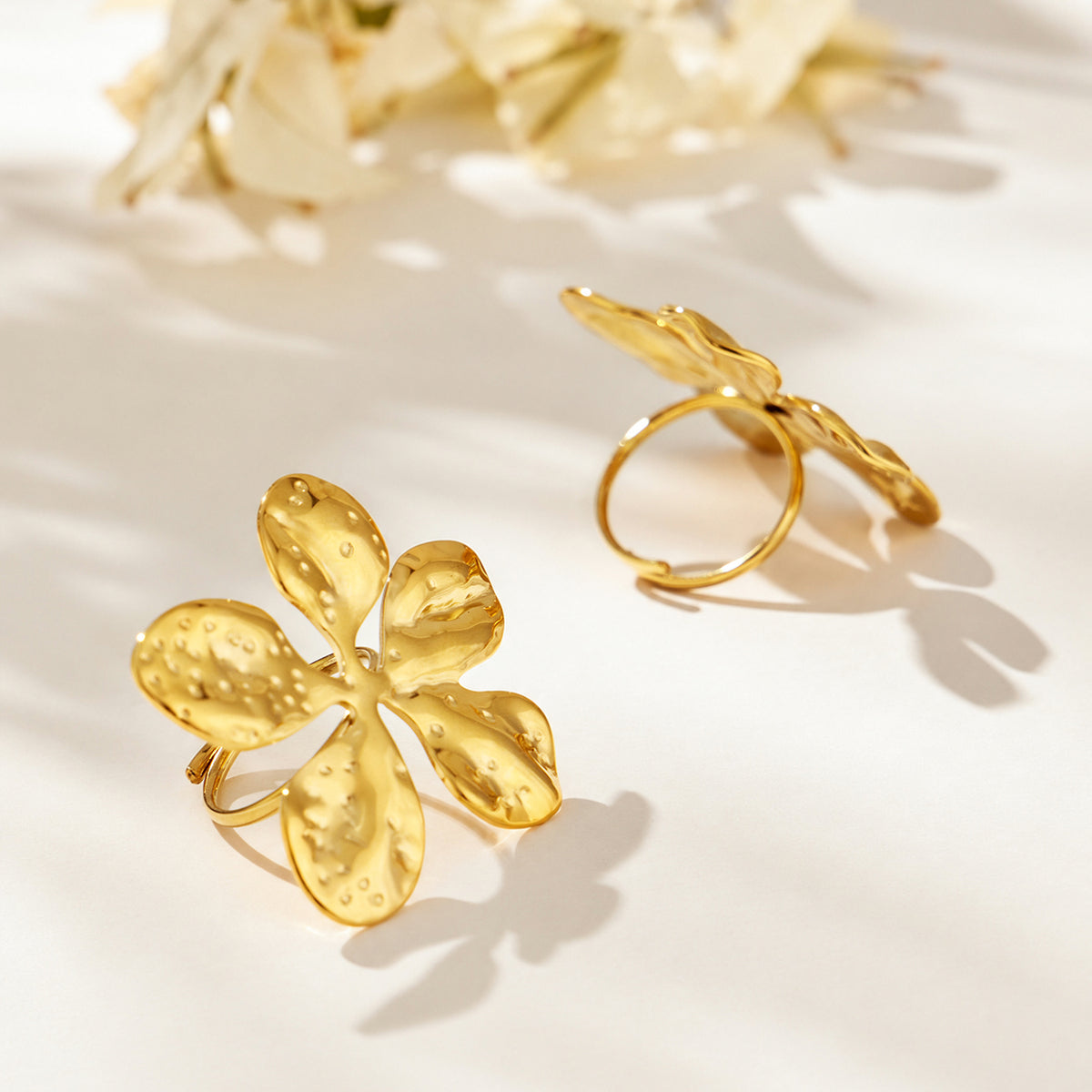 Gold-tone stainless steel flower rings displayed with front and side views of the bands