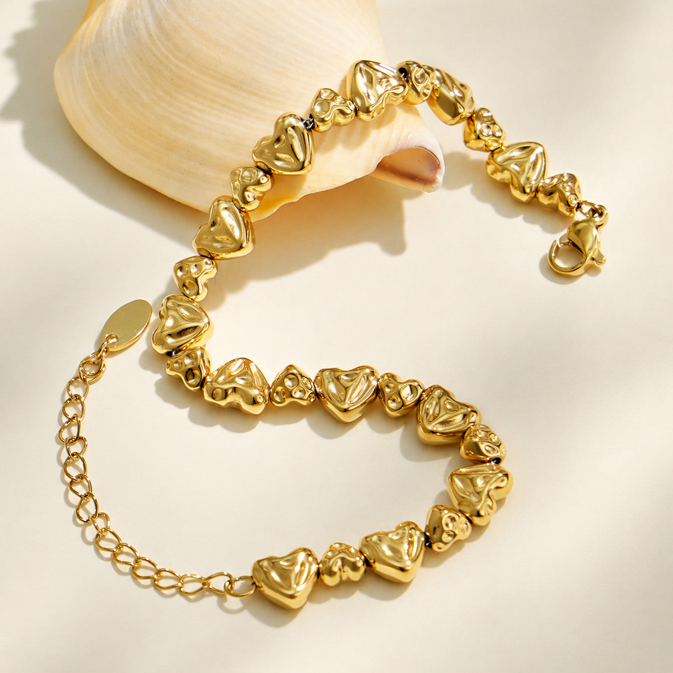 Curved display of a gold hammered heart-link bracelet with sculpted heart motifs